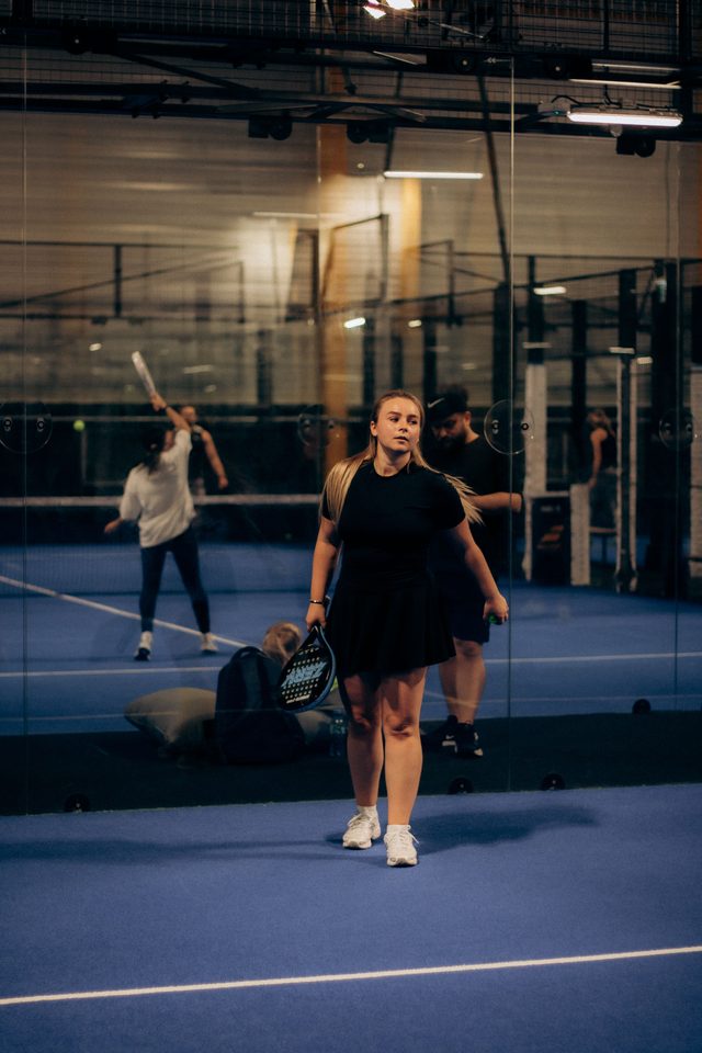 Player ready at the glass with a game going on behind her